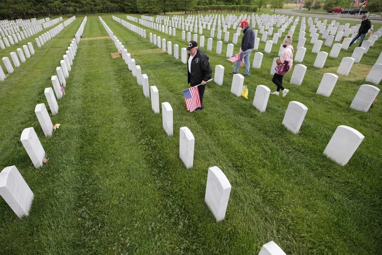 Retired Marine Tom Jankiewicz, (left) who fought in the Vietnam War, places flags at Washington Crossing National Cemetery in Newtown, Pa., on Memorial Day. Jankiewicz is a member of the Marine Corps Law Enforcement Foundation. Joining him from the foundation were G. Daniel Jones (in red hat) and Michael Wallace (far right).