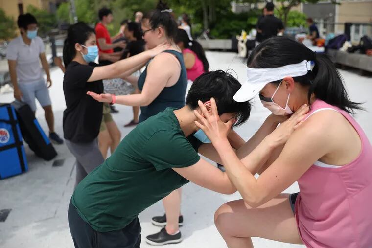 San Li (left), a student at the Philadelphia Wing Chun Kung Fu school, helps Mary Liu practice defending against a front choke during one of the Philly Fighting Asian Hate self-defense classes at the Rail Park last month.
