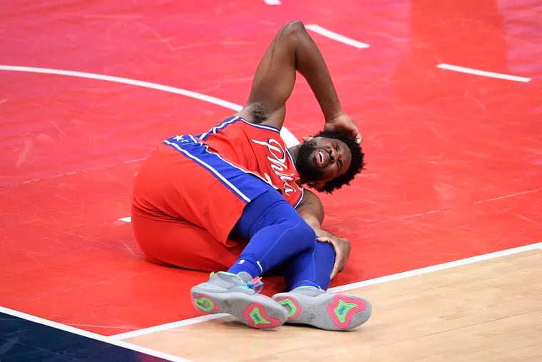 Joel Embiid on the court in pain after suffering his knee injury during the third quarter.