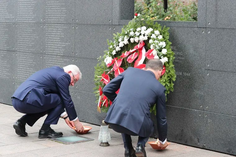 Polish Foreign Minister Jacek Czaputowicz, left, and his German counterpart Heiko Maas, right, pay homage to the victims of the Warsaw Uprising, a failed revolt by Poles against the occupying Nazi German forces, in Warsaw, Poland, Thursday, Aug. 1, 2019 on the 75th anniversary of the start of the two-month battle.