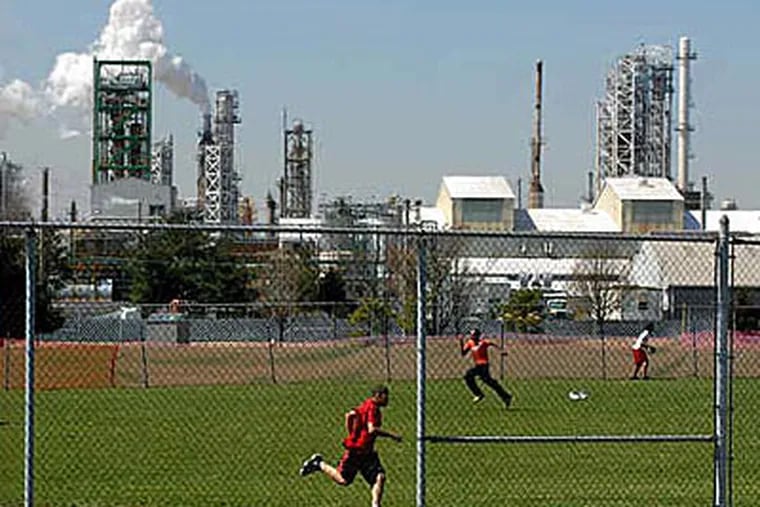 Students at Paulsboro High School play kickball next to an oil refinery. PBF Energy’s refinery plans to lay off 250 employees and halt fuel production as a result of low demand.