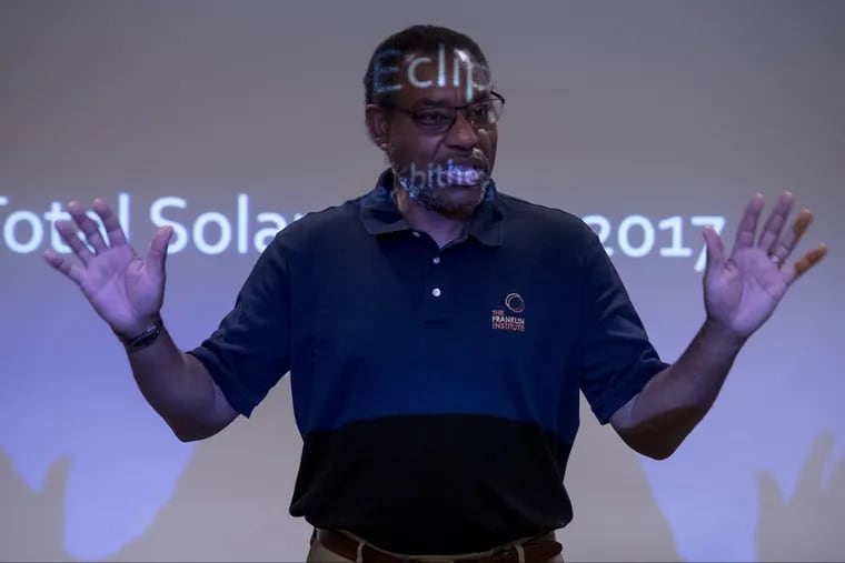 Franklin Institute chief astronomer Derrick Pitts creates a mini eclipse — by standing between the projector and the screen — as he leads a workshop on how to safely view the upcoming solar eclipse.