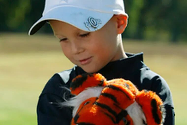 Kyle snuggles his tiger driver cover, which once belonged to Tiger Woods. Kyle was stricken with cancer at 2 - the same age at which he became interested in golf - and lost an eye.