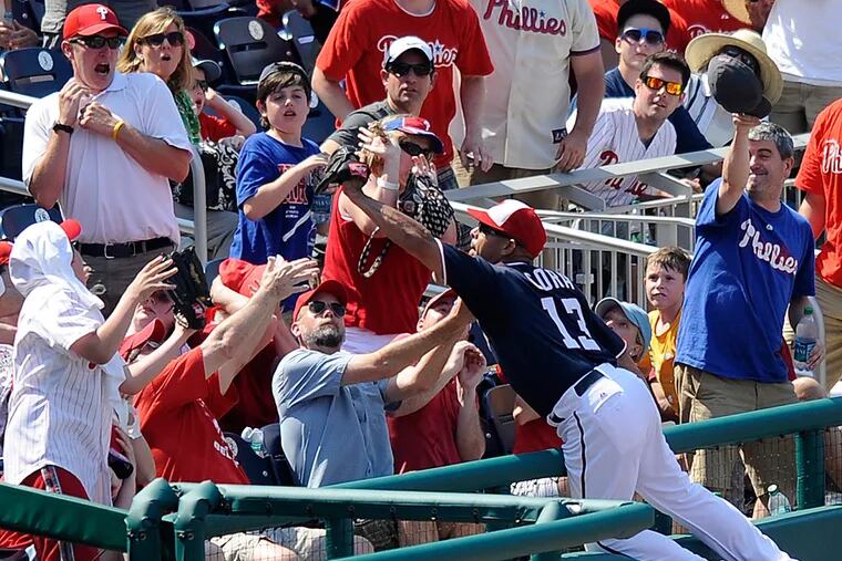 Washington Nationals third baseman Alex Cora reaches into the stands to catch a foul ball by Philadelphia Phillies' Ross Gload during the eighth inning. The Phillies won 5-4. (AP Photo/Nick Wass)
