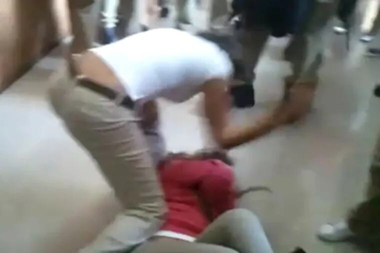 An Edison High School student assaults another student lying on a hall floor in a frame captured from a cellphone video.
