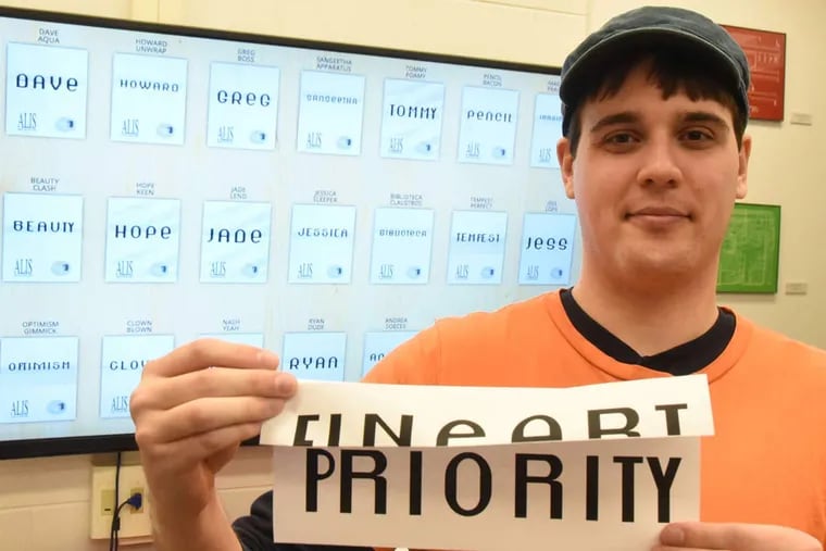 Andy Moffett, a Rutgers-Camden junior from Palmyra, shows an enlarged sample that shows the phrase “fine art” that matched up with “priority.” The pairs match visually when cut in half horizontally.