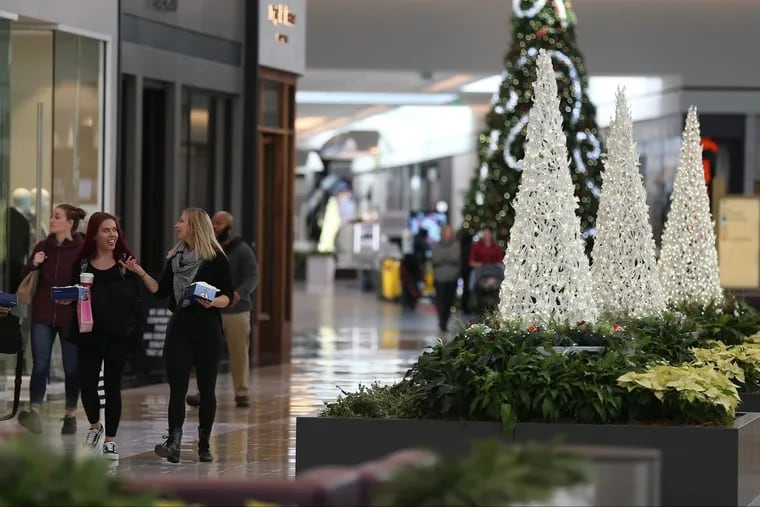 Shoppers pass some of the new holiday displays at the King of Prussia Mall on Tuesday. Merchants and shoppers are preparing for a huge Black Friday.