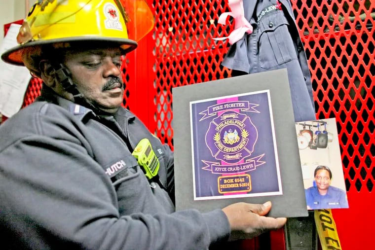 Lt. Hutchins holds a plaque and a photo on Tuesday Dec. 9, 2014, of fallen firefighter Joyce Craig, who died in a house fire in West Oak Lane. (For the Daily News/ Joseph Kaczmarek)