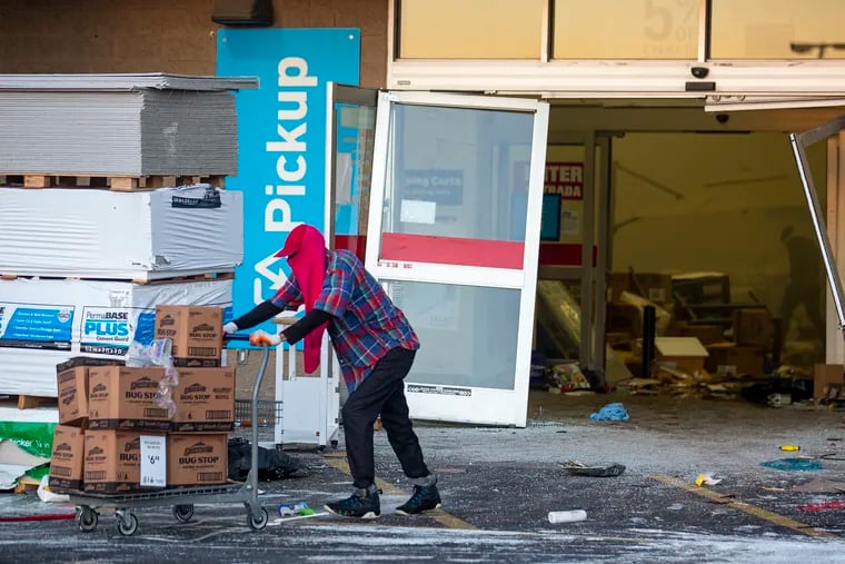 A man pushes a cart loaded with merchandise out of the Lowe's Home Improvement Store during civil unrest at the ParkWest Town Center in West Philadelphia on May 31, 2020.