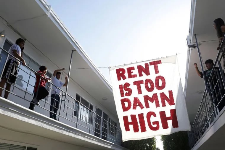 Organizers with Housing Long Beach, a local advocacy group pushing for rent control and eviction protections, hangs up a sign in the courtyard of an apartment complex on Cedar Avenue during a movie night they helped put on with tenants on June 15, 2018 in Long Beach, Calif.