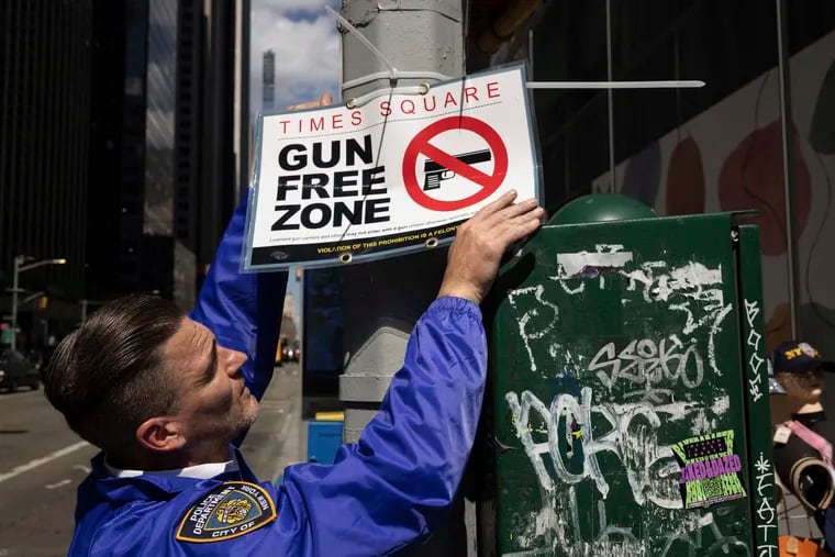 An New York Police Department Public Affairs officer sets up signs reading Gun Free Zone around Times Square.