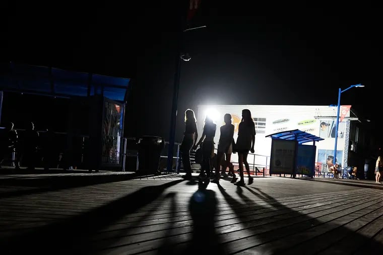 People walk along the Wildwood Boardwalk after the power went out in Wildwood, New Jersey on Friday, July 7, 2023.