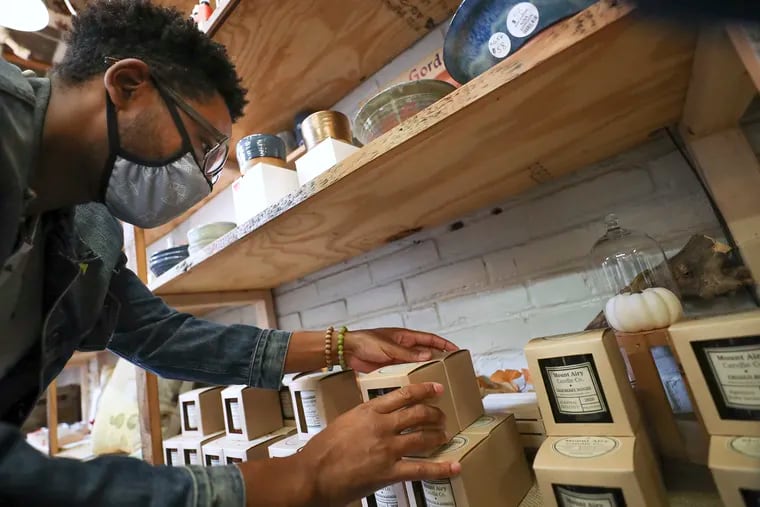 Owner Marques Davis adjusts his display of Mount Airy Candle Co. products at The Mercantile in the West Mount Airy section of Philadelphia on Saturday, Sept. 26, 2020. The company has seen fast growth over the past year.
