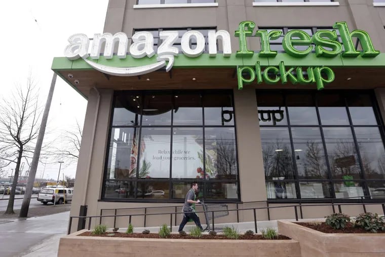 A worker wheels back a cart after loading a bag of groceries into a customer’s car at an AmazonFresh Pickup location in Seattle.