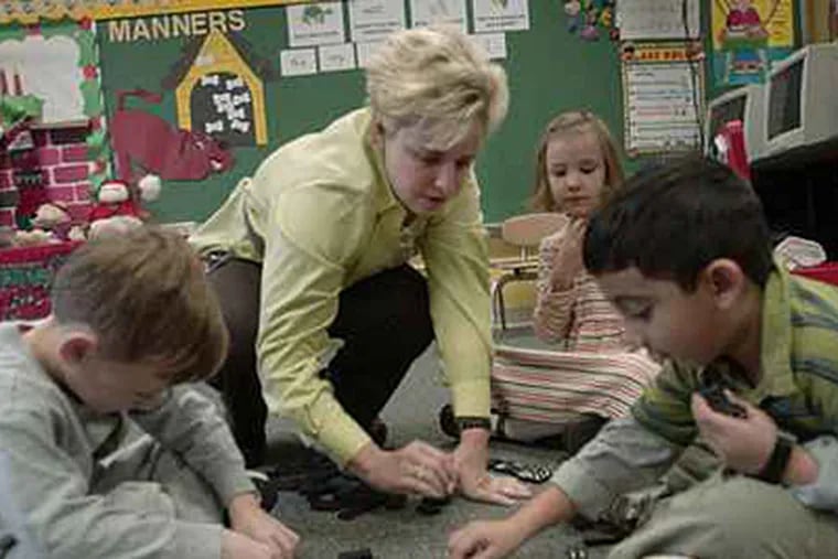Kim Mueller works with Lumberton, N.J. elementary students during a domino game in this file photo. About a fifth of N.J. school districts are planning staff wage freezes or reductions for the coming school year. (Jonathan Wilson / File)