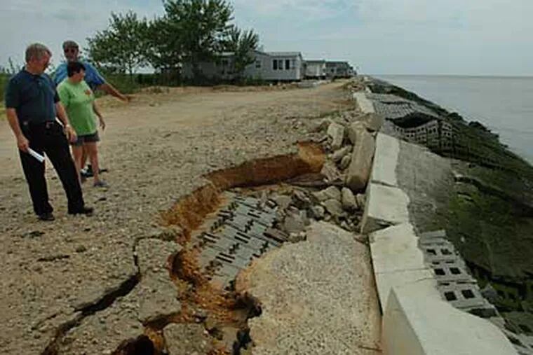 From left, Joe Hepner, and couple Ellie and Bob Spence point out where
a wall has imploded/eroded on Beach Avenue in Sea Breeze. (Sarah J. Glover / Staff Photographer)
