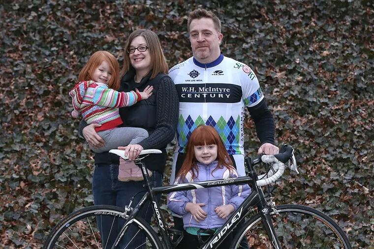 Andrew McIntyre and his wife, Blaire Evelan,  and two daughters, Isla 4 and  Ainslee, 2. He is wearing his cycling jersey, which bears his father's name, the name of the nonprofit foundation McIntyre started. (  STEVEN M. FALK / Staff Photographer )