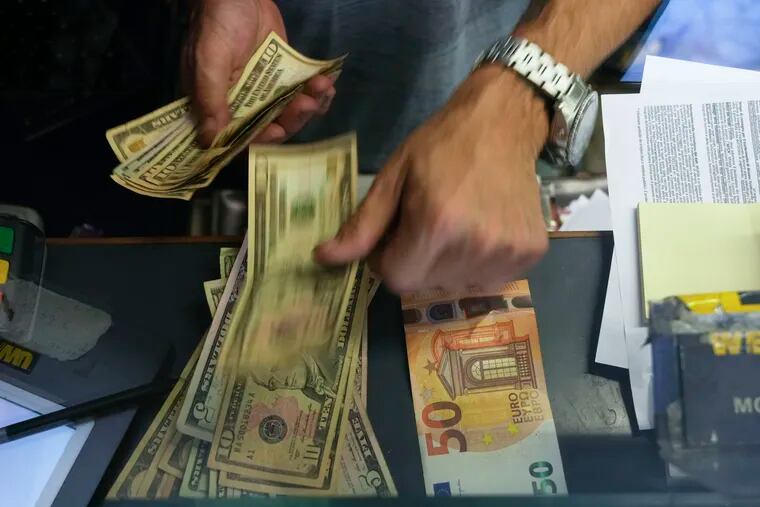 A cashier changes a 50 Euro banknote with U.S. dollars at an exchange counter in Rome.