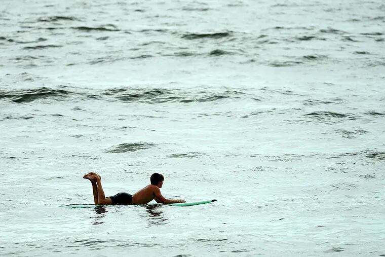 A lone surfer waits for a wave along the Ocean City shore on July 6. The weather could become a lot less calm in the next few days. CLEM MURRAY / Staff Photographer