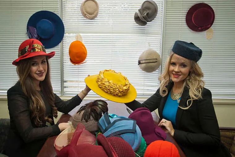 Chelsea Irwin (left) and Natalie Mackey model two of their hats. Their stock started with about 3,000 hats found in a defunct N. Philadelphia shop. (Ron Tarver/Staff Photographer)