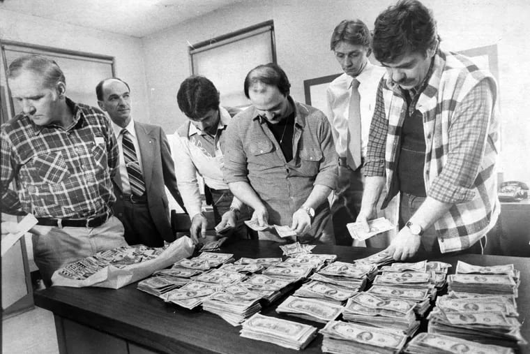 From left: Detective Frances Bresch, Purolator employee Jack Toward, Detectives Martin Mikstas and Pat Laurenzi, Captain Robert Eichler, and Detective James Ptocnaic count money recovered from the Joey Coyle robbery during a February 1981 news conference. File Photograph