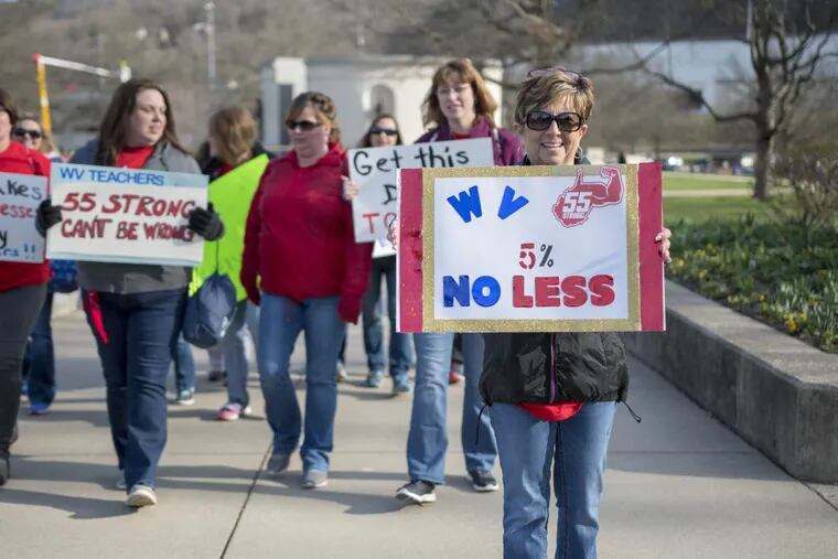 Elizabeth Ferguson Hollifield, a teacher from Princeton W.Va., holds a sign as she walks to a teacher rally Monday, March 5, 2018, at the West Virginia Capitol.