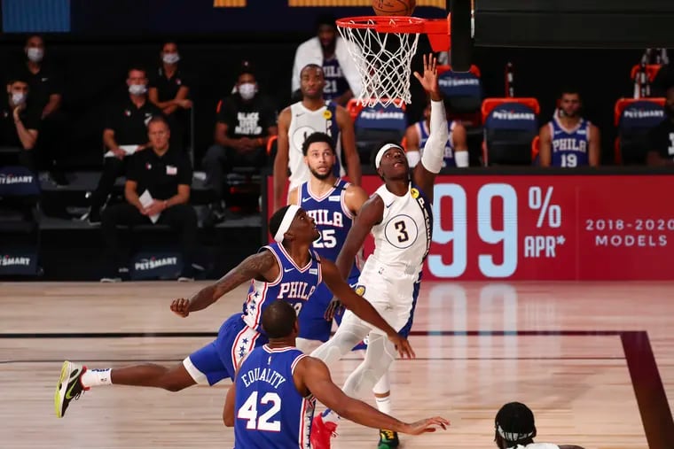 Indiana Pacers guard Aaron Holiday (3) shoots next to  76ers guard Shake Milton.