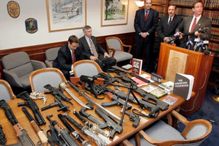 Holding the 9mm weapon that was seized from the home of a 14-year-old boy, Montgomery County District Attorney Bruce L. Castor Jr. displays other objects from the boy&#0039;s house.