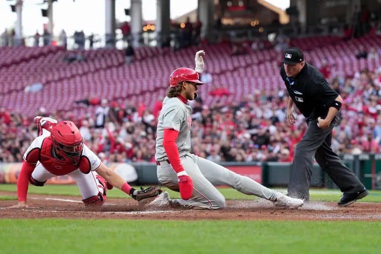 Alec Bohm #28 of the Philadelphia Phillies scores against Tyler Stephenson #37 of the Cincinnati Reds on a sacrifice fly ball hit by Bryson Stott #5 during the second inning of a baseball game at Great American Ball Park on April 22, 2024 in Cincinnati, Ohio.
