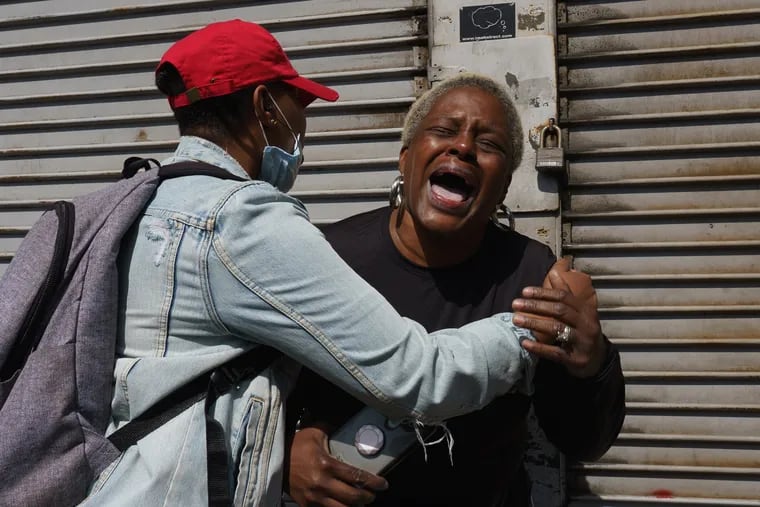 Kita, (left) tries to comfort her Aunt Tracey, a West Philadelphia resident who cried when she saw the damage done to 52nd Street, near Market Street, during the looting and vandalism on Sunday night. (Both woman preferred to be identified by their first names only.)
