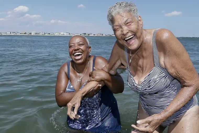 Traci Scott (left) and Delores Mitchell hold on to each other and laugh after they both dove under the water at the Caspian Ave. beach in Atlantic City.