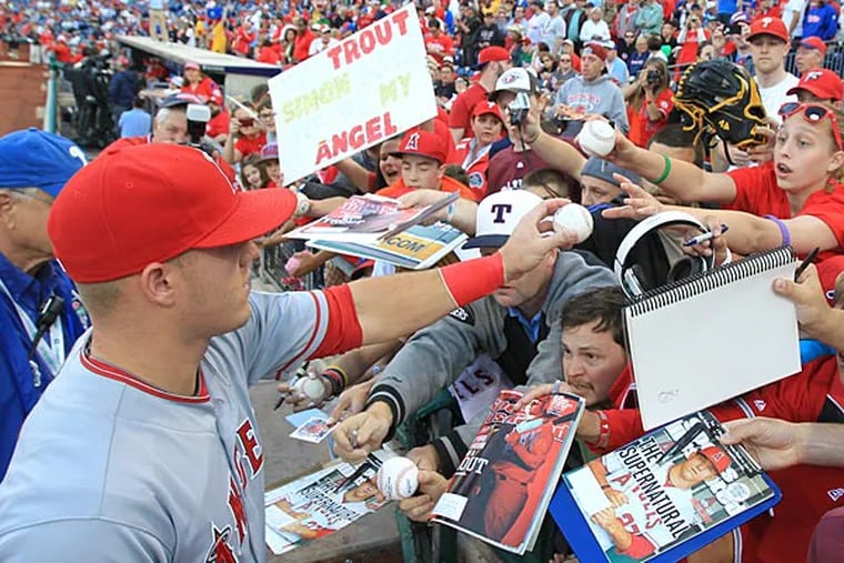 Mike Trout of the Los Angeles Angels is swarmed as he signs autographs.  (Charles Fox/Staff Photographer)