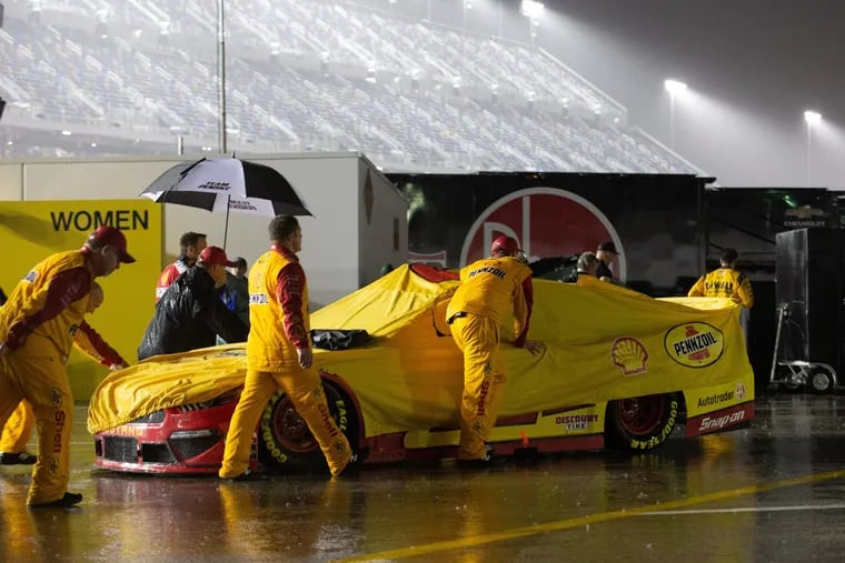 Crew members push the car of Joey Logano, driver of the #22 Team Penske Shell Pennzoil Ford Mustang, after rain postponed the Daytona 500 on Sunday.