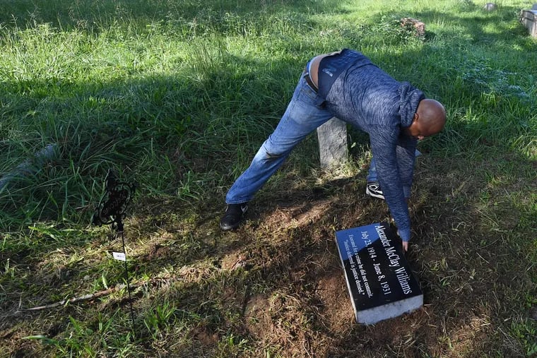 Kwasi Dodson cleans the headstone of his relative, Alexander McClay Williams, during a ceremony at the Green Lawn Cemetery in Aston. Williams was executed at age 16 for a crime many believe he did not commit.