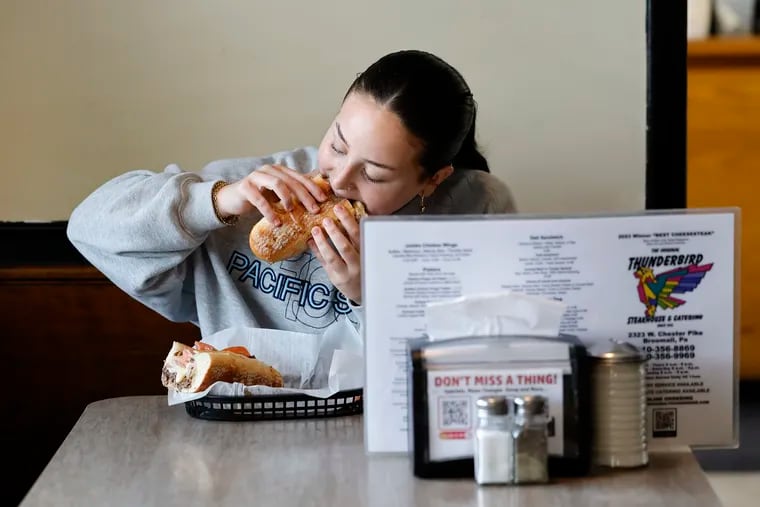 Jade Goffman eats the Thunderbird (T-Bird) Special Cheesesteak with American cheese, deluxe ham and sliced tomato at the Original Thunderbird Steakhouse & Catering in Broomall, PA on Monday, May 20, 2024.