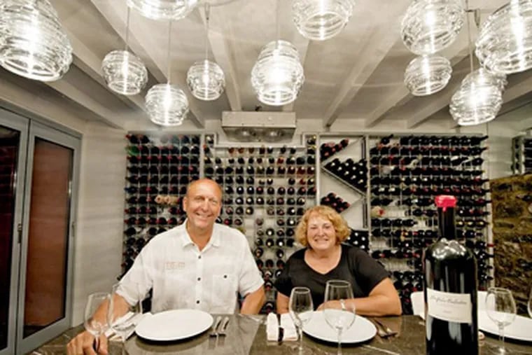 Eric and Lee Miller sit at the table in the climate-controlled wine cellar of their renovated townhouse in West Chester. (CLEM MURRAY / Staff Photographer)