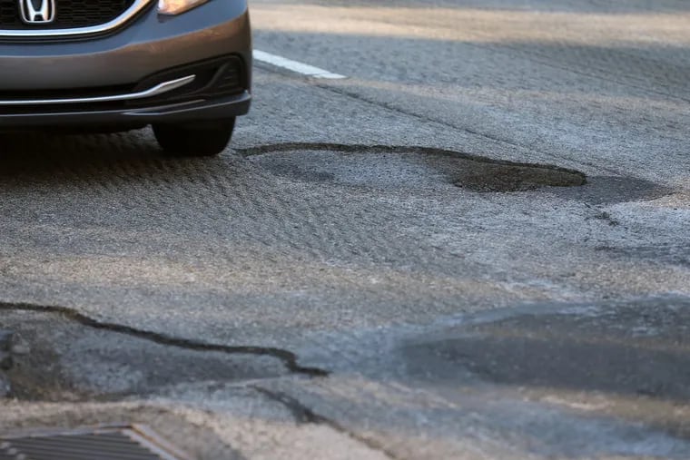 A car avoids a pothole on Lincoln Drive near Gypsy Lane in Philadelphia on January 14, 2018.