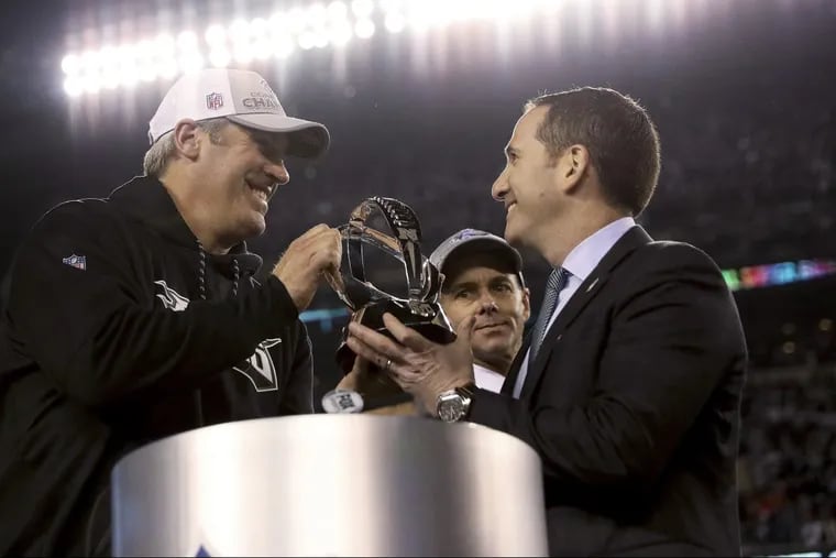 FILE – In this Sunday, Jan. 21, 2018, file photo Philadelphia Eagles coach Doug Pederson, left, and Howie Roseman, right, the team's executive vice president of football operations, hold the NFC championship trophy after the Eagles' 38-7 win over the Minnesota Vikings in the NFC championship NFL football game in Philadelphia. After finishing last in the NFC East last season, the Eagles are in the Super Bowl. Radio hosts, columnists, writers, fans and even bloggers are not blasting Roseman anymore because he made all the right moves to build a team one victory away from the franchise's first NFL title since 1960. (David Maialetti/The Philadelphia Inquirer via AP, File)