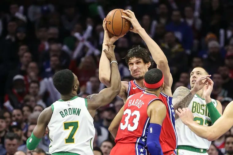 Sixers' Boban Marjanovic grabs a rebound between Celtics'  Jaylen Brown (7) and Daniel Theis during the 3rd quarter at the Wells Fargo Center in Philadelphia, Tuesday, February 12, 2019. Celtics beat the Sixers   112-109.