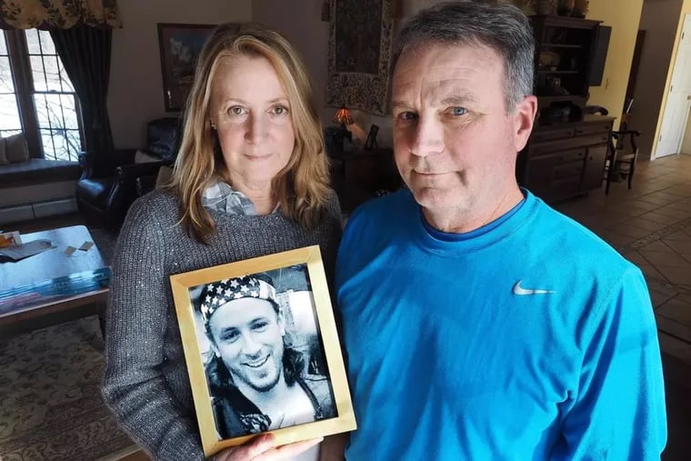 Jeanne and Jim Moser pose with a photo of their son Adam, who died of an overdose in September 2015.