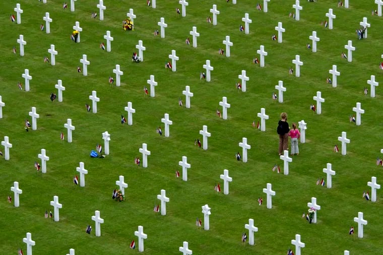 People pause at a grave with the Star of David amidst other graves ahead of Memorial Day at the Netherlands American Cemetery in Margraten, southern Netherlands. A total of 8,302 war veterans and war victims are buried at the cemetery. Photos of more than 7,500 of the U.S servicemen and women buried or commemorated at Margraten were due to be displayed next to graves in Margraten this week as Europe commemorates the 75th anniversary of the end of World War II, but the event was cancelled due to COVID-19 coronavirus related measures.