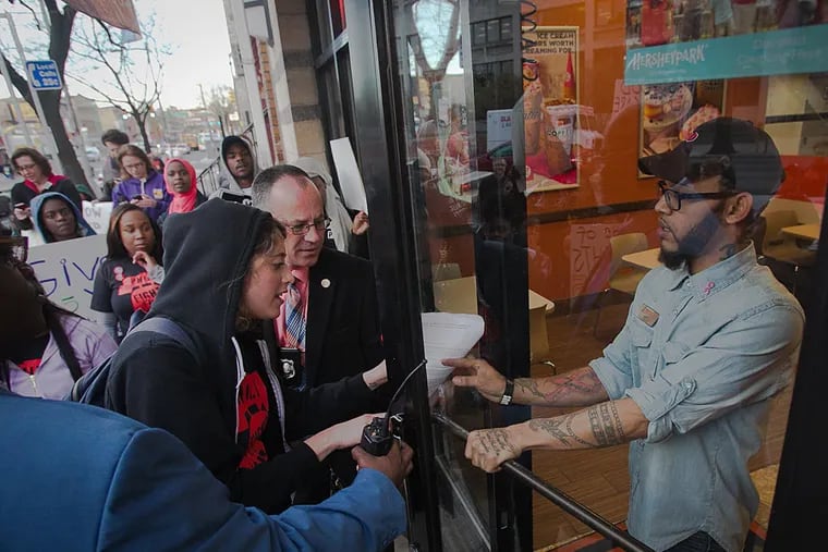A strike organizer hands a letter from the Pennsylvania Workers Organizing Committee to a Dunkin Donuts worker on N. Broad St., explaining that a Dunkin Donuts employee at that location is on strike. The strike is part of the Fight for $15 gather protests being held around the nation. ( ALEJANDRO A. ALVAREZ / Staff Photographer)