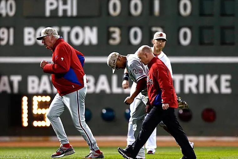 Philadelphia Phillies manager Charlie Manuel, left, walks off the field with Ben Revere (2) after Revere hit the wall fielding a ball hit by Boston Red Sox's David Ortiz in the fourth inning of a baseball game in Boston, Monday, May 27, 2013. (AP Photo/Michael Dwyer)