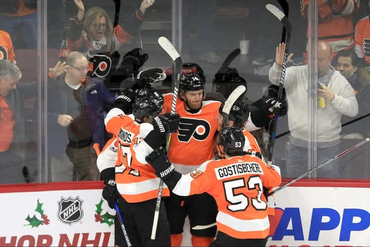 The Flyers’ Sean Couturier, center, is swarmed by teammates after his goal broke a 2-2 deadlock against the Maple Leafs.