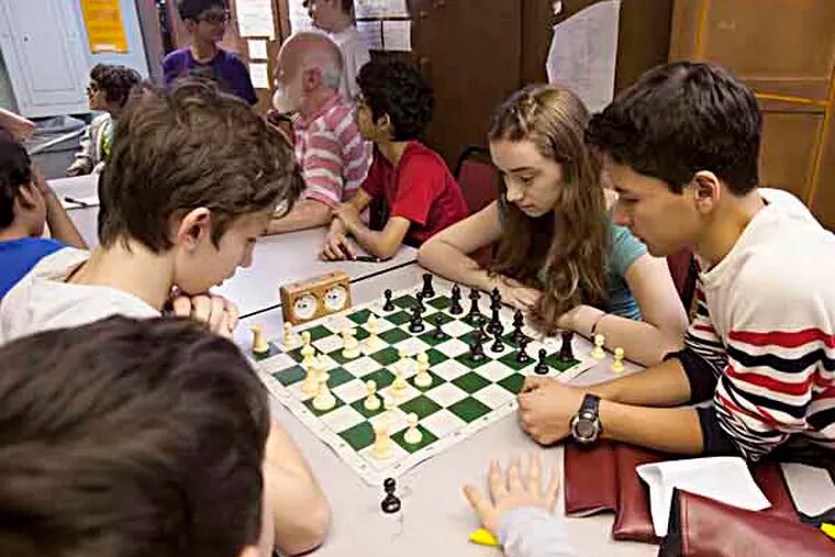 Masterman Middle School's award-winning chess team has their most recent triumph , the national championship. Photographed at school on Thursday April 11th, Alex Wlezien, 14, left, and Shira Moolten,13, right face off in a chess match in the basement of Masterman Middle School as they are watched by teammates including Alejandro Budejen-Jerez, far right and Torin Kuehnle, far left. ( ED HILLE / Staff Photographer )