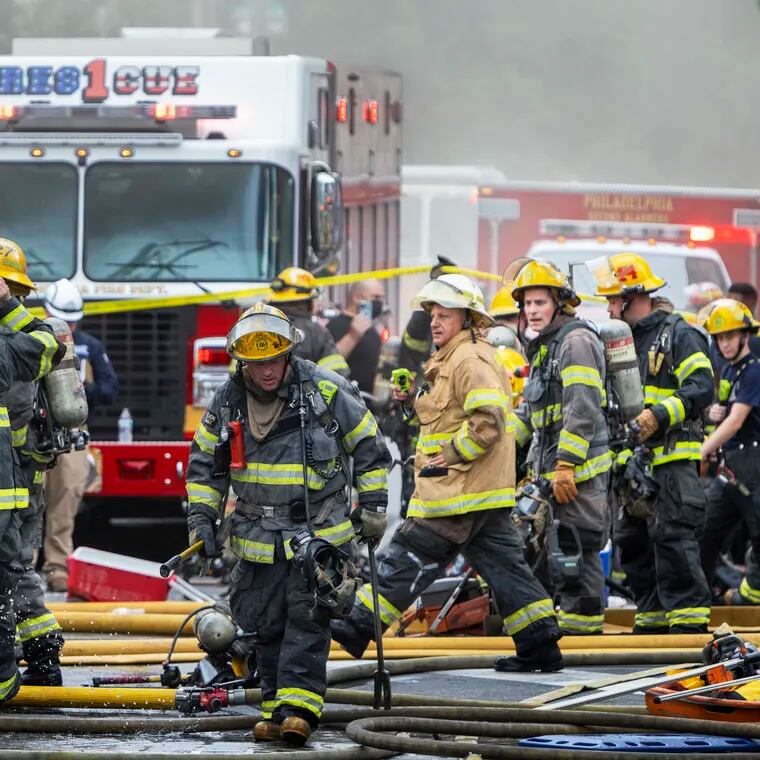Philadelphia Fire Department personnel gather on the scene of a fire in July 2022. The department announced this week that it will reopen three companies that were shuttered in 2009 as a cost-cutting measure.
