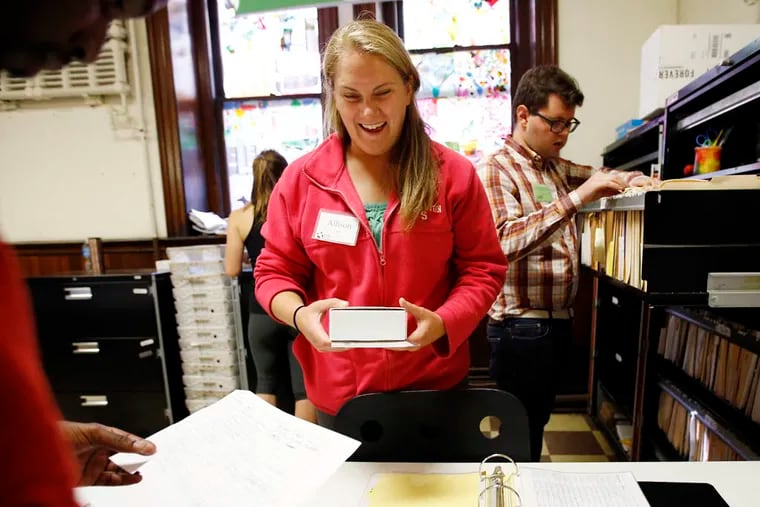 Volunteer Allison Davis hands out mail at the Broad Street mail service located inside the the Broad Street Ministry on Wednesday, October 8, 2014.  ( YONG KIM / Staff Photographer )