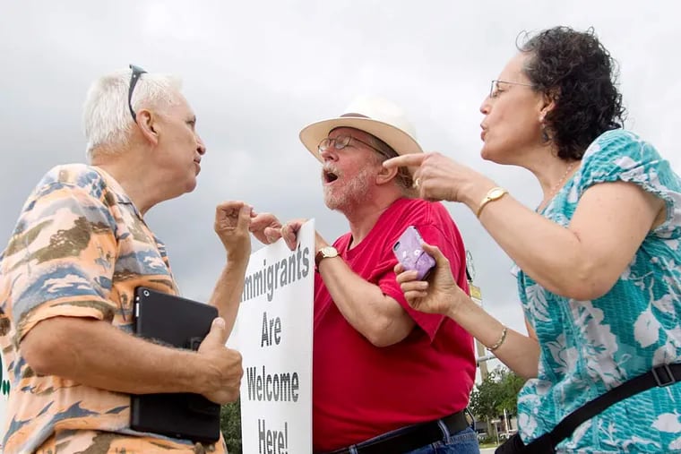 Immigration supporters David Smith, center, and Rona Smith debate with an anti-immigration protester on Saturday, Aug. 2, 2014, in Conroe, Texas. Texas Gov. Rick Perry plans to use $38 million in emergency funds to begin the deployment of up to 1,000 National Guard troops along Texas' border with Mexico, his office said. Perry intends to use the Guardsmen to help law enforcement as a surge of people from Central America, including thousands of children, crosses into the United States. (AP Photo/Conroe Courier, Jason Fochtman)