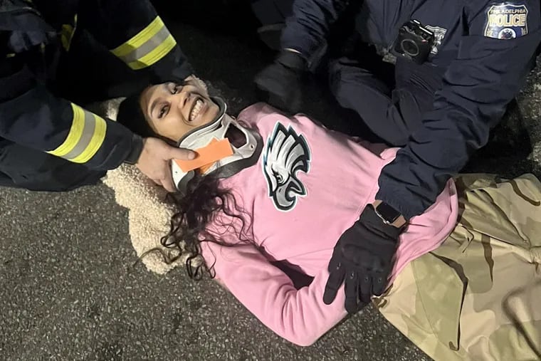 Ashley "Kilos" Mar was one of the Eagles fans who fell from a bus shelter in Center City when it collapsed amid celebrations after the Eagles won the NFC championship on Sunday. Paramedics tend to her after the collapse and put her in a neck brace.