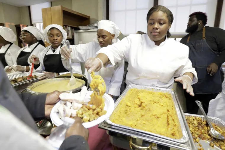 Kyarah Wallace (right) serves up sweet potatoes during a Thanksgiving community event at Dobbins CTE H.S. on November 18, 2016.